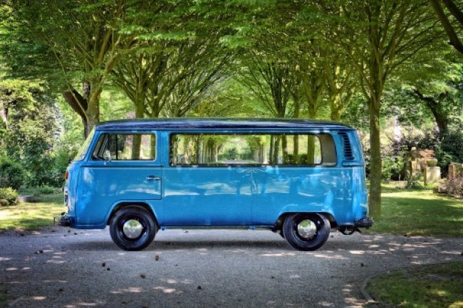 Blue rebuild VW Van to hearse in sunny graveyard with trees